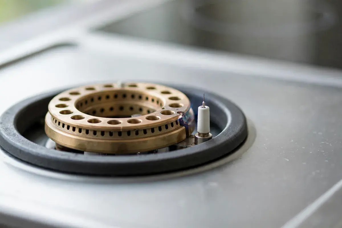 Gas range burner head and igniter shown closely on a clean cooktop