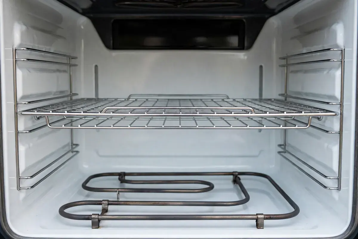 Inside of an electric oven showing the bake element and a clean rack